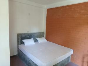 uma cama numa parede de tijolos com duas almofadas em Mango Roots em Gampaha