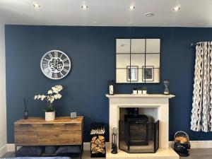 a living room with a fireplace and a clock on the wall at Modern Retreat with Hot Tub and Cinema in Cuckney
