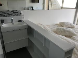 a white bathroom with a sink and a mirror at Studio face Mer - Village Naturiste - Cap d'Agde in Cap d'Agde +4 photos