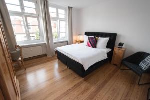 a bedroom with a bed and a chair and two windows at Modern design im klassischem Altbau in Weimar