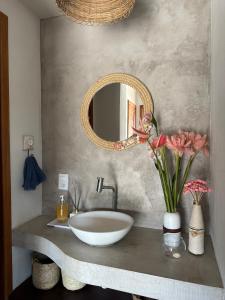 a bathroom with a sink and a mirror and flowers at Casa de praia exclusiva, pé na areia em Mogiquiçaba, Bahia in Belmonte +17 photos