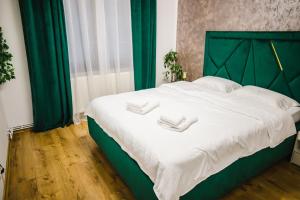 Una cama verde con dos toallas blancas. en Melissa Home, en Bucarest
