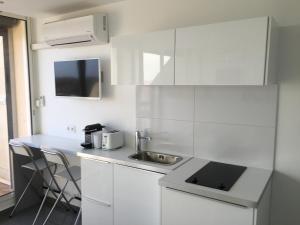 - une cuisine blanche avec évier et comptoir dans l'établissement Studio face Mer - Village Naturiste - Cap d'Agde, au Cap d'Agde