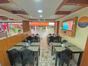 a restaurant with tables and chairs and a large screen at Airport Hotel Link Asia in Bākhri Kharka