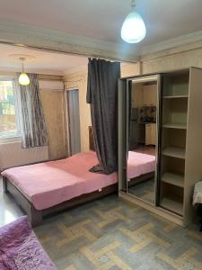1 dormitorio con 1 cama con sábanas rosas y espejo en Rusalka, en Kobuleti