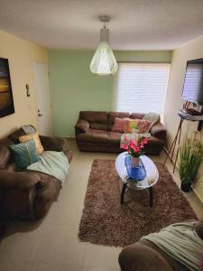 a living room with couches and a table with flowers on it at Apartmento Minutos Caracola Beach in Porlamar