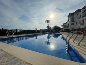 ein großes Schwimmbecken mit blauem Wasser und Gebäuden in der Unterkunft El Valle Golf Resort in Baños y Mendigo
