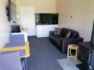 un salon avec un canapé noir et une télévision dans l'établissement Hot Water Beach Lookout B&B, à Hahei