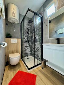 a bathroom with a shower with a toilet and a red rug at Apartments Hajl in Krk +36 photos