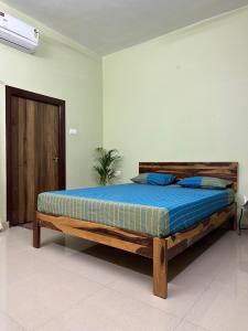 1 dormitorio con cama de madera con sábanas azules en Veridian Villa, en Kānpur