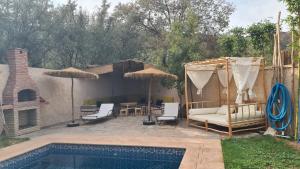 a pool with chairs and umbrellas next to a house at Ouirgane House in Ouirgane