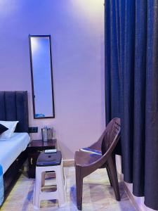 a bedroom with a bed and a chair and a mirror at Shyam Residency - 50 mtr from Ram Mandir in Ayodhya +3 photos