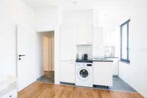 a white kitchen with a washing machine in it at Cozy Brabanconne apartment in Brussels