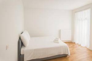 a white bedroom with a bed with white sheets at Cozy Brabanconne apartment in Brussels