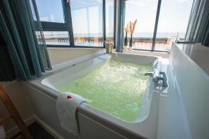 een badkuip gevuld met groen water met een handdoek bij Slapen in een Trechter in Harlingen