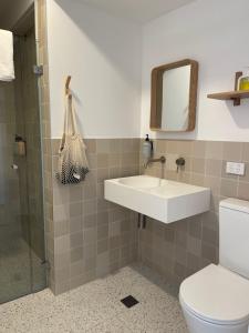 a bathroom with a sink and a toilet and a mirror at Archy's on the Lake in Burrill Lake