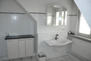 a white bathroom with a sink and a mirror at Ferienwohnung Schulte in Paderborn