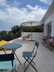 a patio with tables and chairs and an umbrella at Villa Pietranera in San-Martino-di-Lota