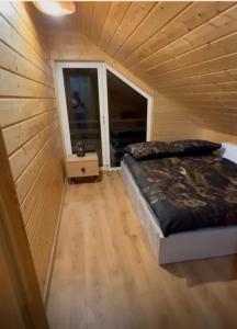 een slaapkamer met een bed in een houten hut bij Domek na Kaszubach u Doroty 