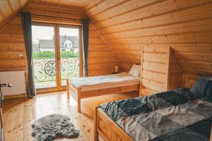 a log cabin with two beds and a window at Dziki Raj - domki z widokiem na Tatry oraz Babią Górę in Jabłonka