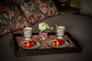 a tray with two cakes and two cups on a bed at Pasaku apartaments in Cēsis