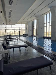 a large swimming pool with tables in a building at Aeon Towers 2BR in Sheikh Zayed