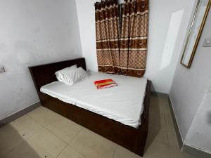 Una cama pequeña con sábanas blancas y un libro rojo encima. en Hotel Labbaik Farmgate, en Dhaka