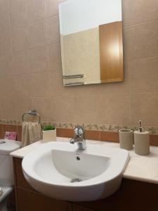 a bathroom with a white sink and a mirror at Tranquil Poolside apartment with stunning views in Mazotos +10 photos