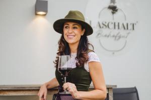 a woman wearing a hat holding a glass of wine at Biohofgut LASCHALT in Deutsch Kaltenbrunn