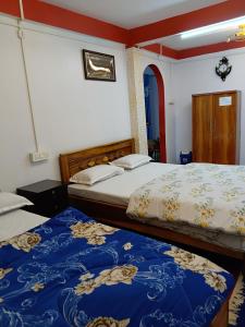 a bedroom with two beds with blue and white sheets at Bloomfield Farmhouse 2 in Darjeeling
