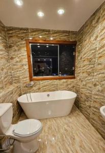 a bathroom with a tub and a toilet and a window at Hany pyramids view in Cairo