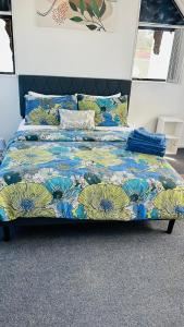 a bed with a colorful comforter on top of it at Mount Breeze in Mount Maunganui