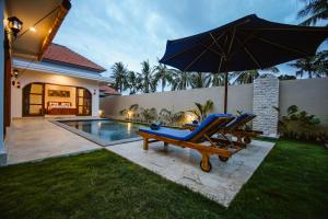 a pool with two blue lounge chairs and an umbrella at Bukti Garden Villas in Bukti