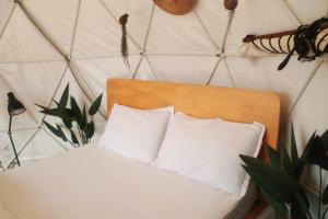 a bed with white sheets and pillows in a room at A'moss Farmstay in Cameron Highlands