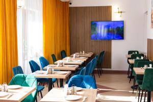 a dining room with tables and chairs and a tv on the wall at Long Street Hotel in Braşov +26 photos