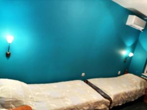 two beds in a room with a blue wall at Galina apartment in Ruse