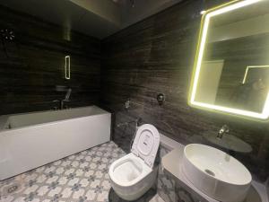 a bathroom with a toilet and a sink and a tub at Hotel Mood Premium By Glitz Hotels in Vasai +6 photos