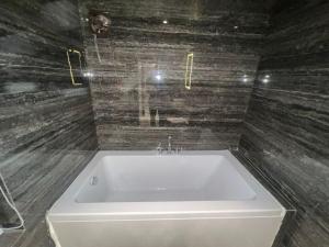 a white bath tub in a bathroom with wooden walls at Hotel Mood Premium By Glitz Hotels in Vasai