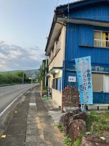 a blue building with a sign next to a street at 二段ベッドの宿青と白 in Aki