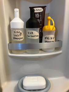 a refrigerator shelf with bottles and other items in it at 二段ベッドの宿青と白 in Aki