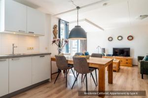 a kitchen and dining room with a table and chairs at Residentie Californië in De Koog