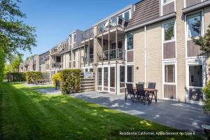 a building with chairs and a table in front of it at Residentie Californië in De Koog