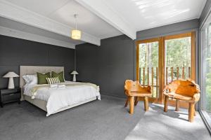 a bedroom with a large bed and a chair at Tranquill 4BR Retreat in Sassafras