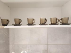 a row of coffee cups sitting on a shelf at Vaikiki Apartman LM in Novi Pazar +25 photos