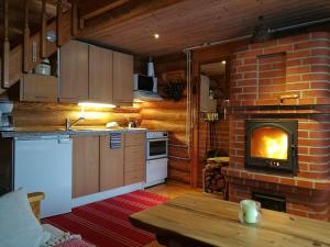 a kitchen with a brick fireplace and a stove at Hirsimökki Villa Lummelahti in Savitaipale