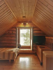a attic room with a bed and a window at Hirsimökki Villa Lummelahti in Savitaipale