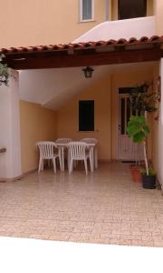 a patio with two white chairs and a table at Villa Olivia Residence Ischia - nel Verde con Piscine e Vista Mare in Forio d'Ischia