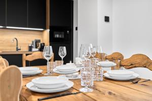 a wooden table with plates and wine glasses on it at Apartment K&L Boží Dar in Boží Dar