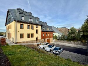 two cars parked in a parking lot in front of a house at Apartment K&L Boží Dar in Boží Dar