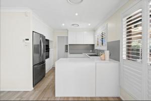 a kitchen with white cabinets and a stainless steel refrigerator at Southern Sky Villa in Ingleburn